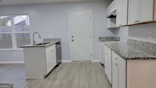 kitchen with dark stone countertops, white cabinetry, sink, and light hardwood / wood-style flooring