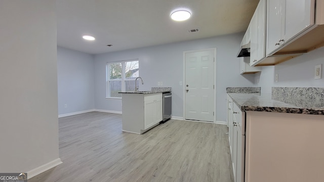 kitchen with white cabinets, sink, dark stone countertops, light wood-type flooring, and kitchen peninsula