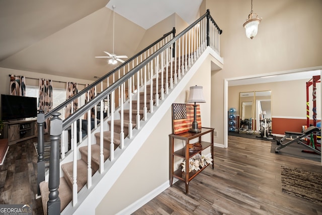 stairs featuring hardwood / wood-style floors, high vaulted ceiling, and ceiling fan