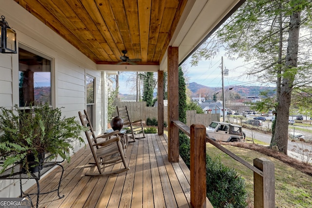 wooden terrace featuring ceiling fan, a mountain view, and a porch