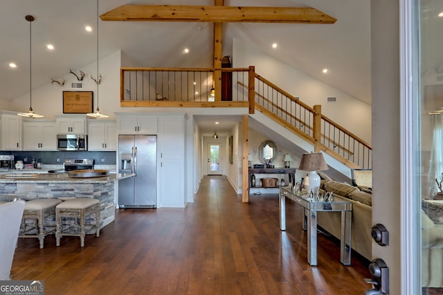 kitchen with appliances with stainless steel finishes, white cabinets, hanging light fixtures, and high vaulted ceiling