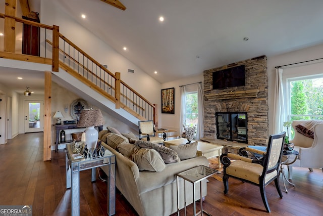 living room featuring a high ceiling, dark hardwood / wood-style floors, and a stone fireplace