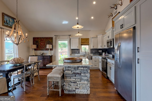 kitchen with decorative light fixtures, appliances with stainless steel finishes, white cabinetry, and a kitchen island