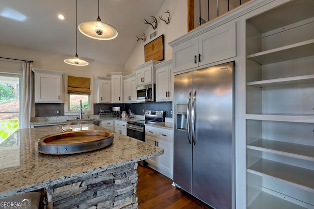 kitchen with appliances with stainless steel finishes, light stone counters, white cabinetry, and pendant lighting