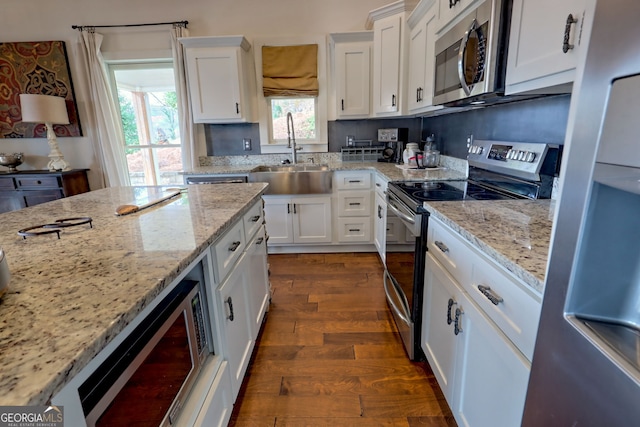 kitchen featuring sink, white cabinetry, light stone countertops, appliances with stainless steel finishes, and dark hardwood / wood-style flooring