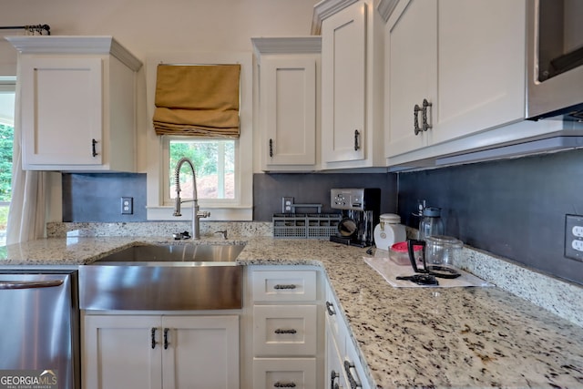 kitchen with light stone counters, sink, white cabinets, and stainless steel dishwasher