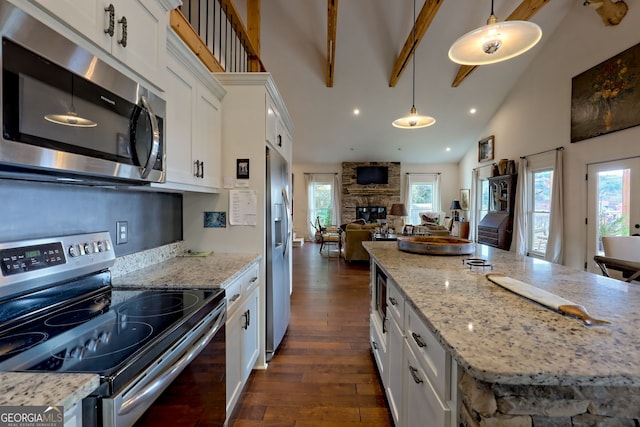 kitchen with beamed ceiling, white cabinetry, hanging light fixtures, a stone fireplace, and stainless steel appliances