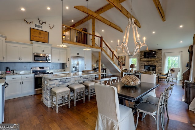 dining space with dark hardwood / wood-style flooring, high vaulted ceiling, a stone fireplace, and beamed ceiling