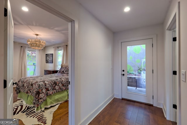 entryway featuring dark wood-type flooring and an inviting chandelier