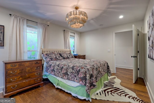 bedroom with wood-type flooring, an inviting chandelier, and multiple windows