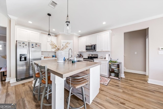 kitchen featuring sink, stainless steel appliances, pendant lighting, white cabinets, and light wood-type flooring