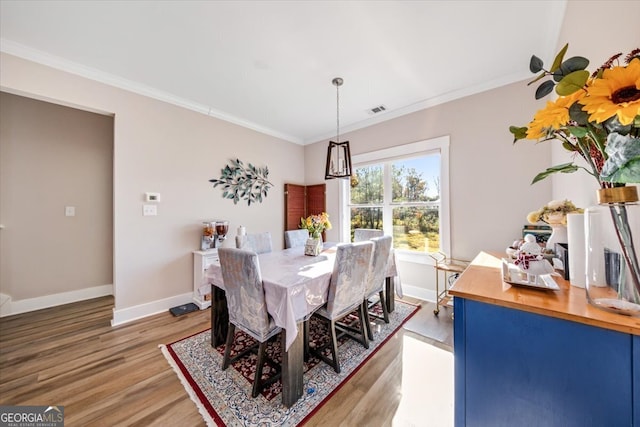 dining area with hardwood / wood-style flooring and ornamental molding