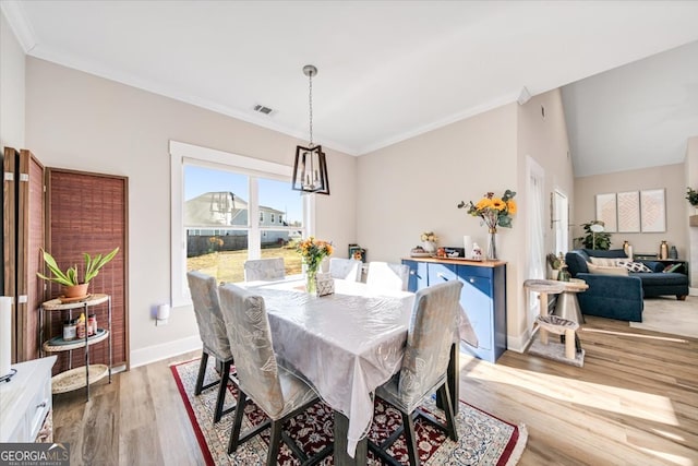 dining room featuring lofted ceiling, light hardwood / wood-style flooring, and crown molding