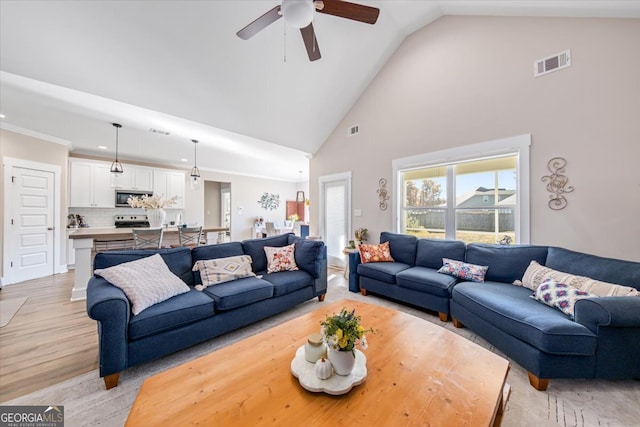 living room featuring ceiling fan, light wood-type flooring, and high vaulted ceiling