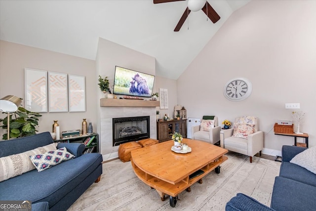 living room with a tiled fireplace, ceiling fan, and high vaulted ceiling