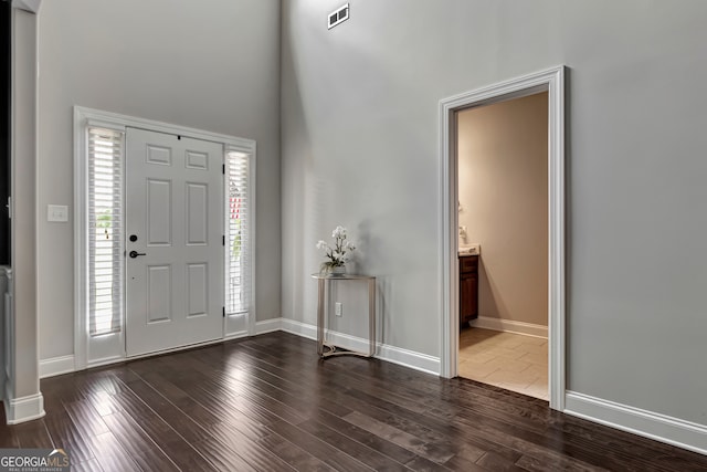 foyer entrance featuring dark hardwood / wood-style flooring and a towering ceiling