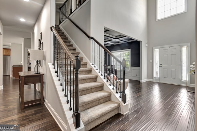 foyer featuring a towering ceiling, dark wood-type flooring, and coffered ceiling