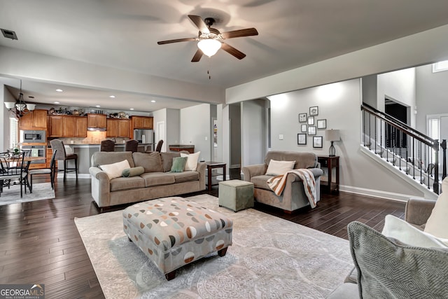 living room featuring ceiling fan with notable chandelier and dark hardwood / wood-style floors