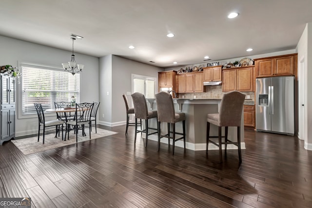 kitchen featuring dark hardwood / wood-style floors, hanging light fixtures, stainless steel refrigerator with ice dispenser, and a wealth of natural light