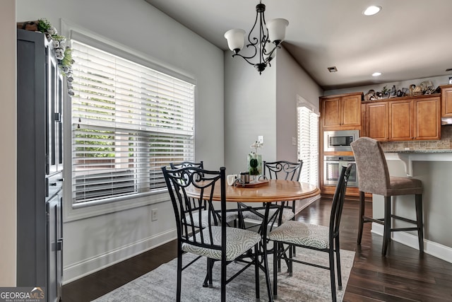 dining area with dark hardwood / wood-style floors and an inviting chandelier