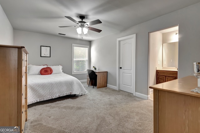 bedroom featuring light carpet, ensuite bath, and ceiling fan