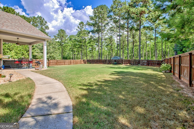 view of yard with ceiling fan and a patio