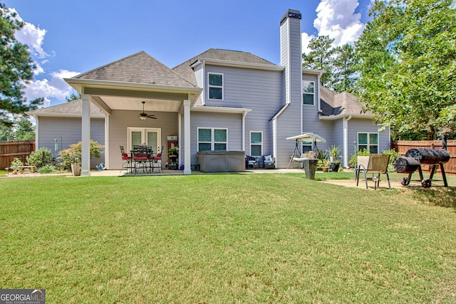 rear view of house with ceiling fan, a patio area, and a lawn