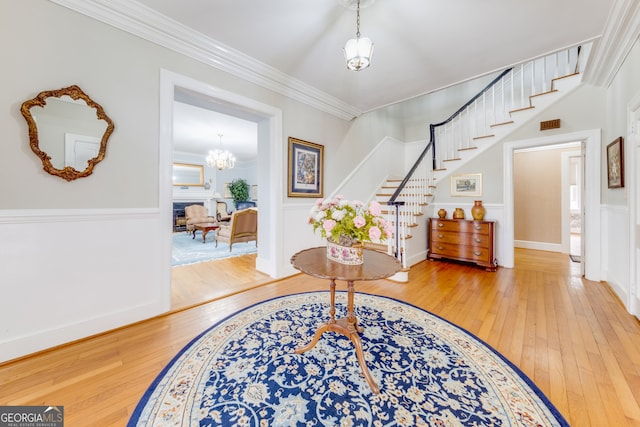 entryway with a chandelier, hardwood / wood-style floors, and ornamental molding