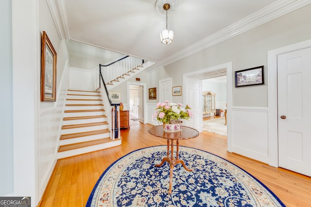 entryway with hardwood / wood-style floors, crown molding, and an inviting chandelier