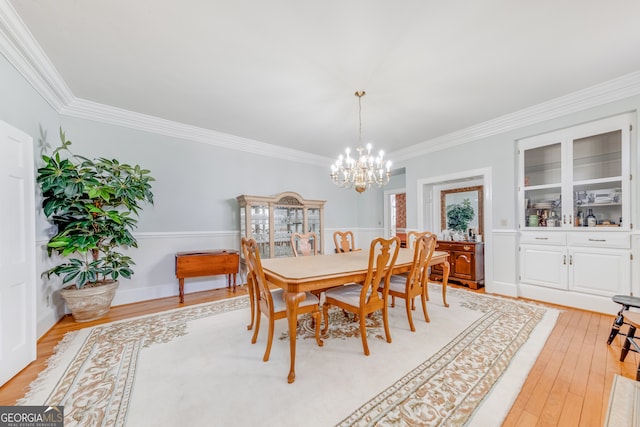 dining space with crown molding, light hardwood / wood-style floors, and a notable chandelier