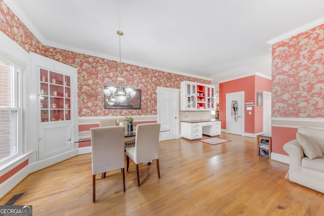 dining room featuring hardwood / wood-style flooring, crown molding, and an inviting chandelier