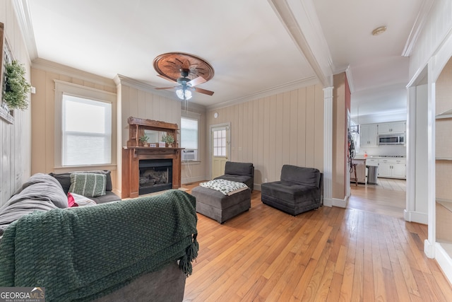 living room featuring decorative columns, ceiling fan, light hardwood / wood-style floors, and ornamental molding