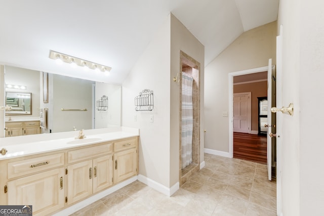 bathroom featuring a shower, vanity, lofted ceiling, and tile patterned flooring