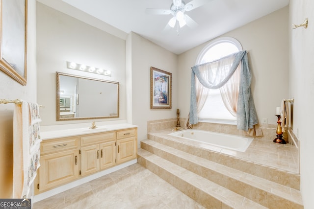 bathroom with tile patterned floors, tiled tub, ceiling fan, and vanity