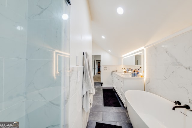 bathroom featuring vanity, lofted ceiling, a bathing tub, tile patterned flooring, and tile walls