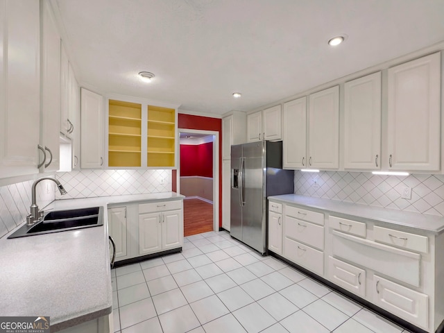 kitchen with decorative backsplash, stainless steel fridge, white cabinetry, and sink