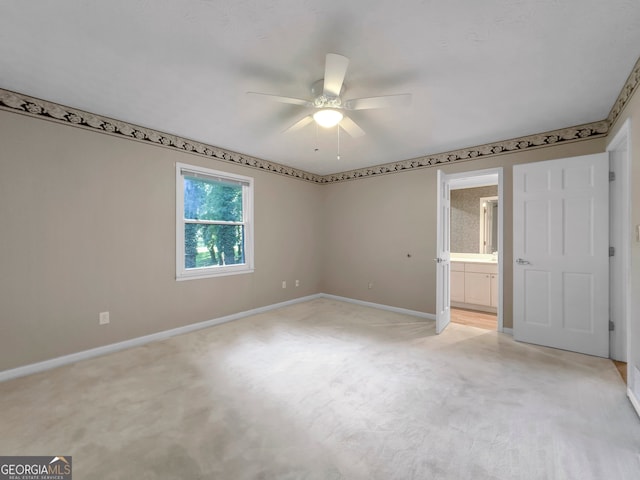 unfurnished bedroom featuring ceiling fan, light colored carpet, and ensuite bath