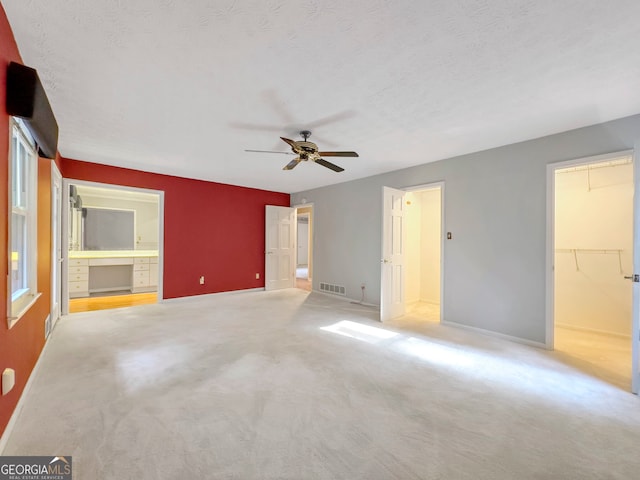 unfurnished bedroom featuring a textured ceiling, light colored carpet, and ceiling fan