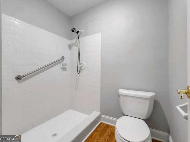 bathroom featuring hardwood / wood-style floors, toilet, and tiled shower