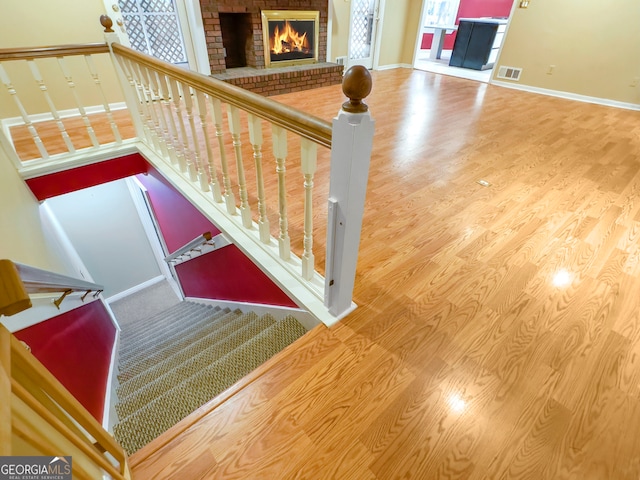 staircase featuring a brick fireplace and hardwood / wood-style flooring