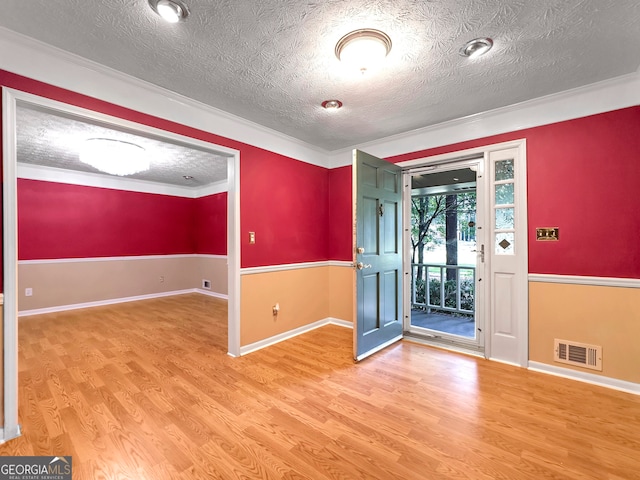 foyer featuring light hardwood / wood-style floors, ornamental molding, and a textured ceiling