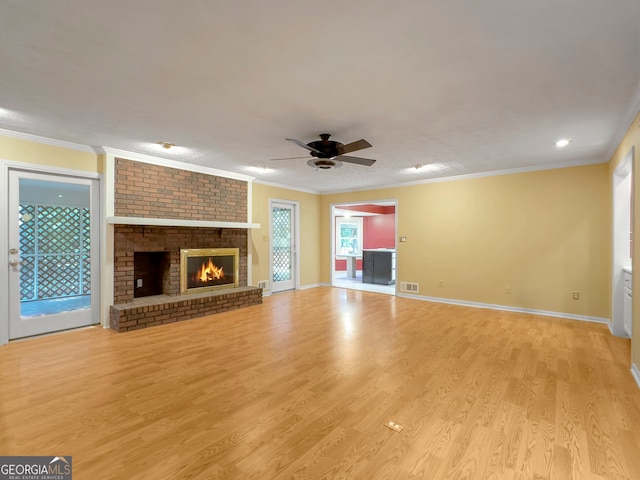 unfurnished living room with ceiling fan, light wood-type flooring, a fireplace, and ornamental molding