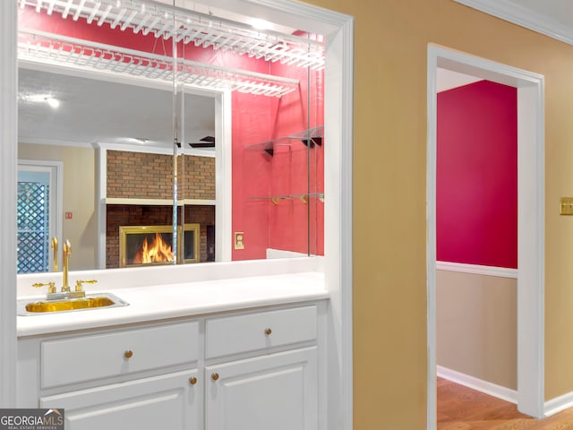 bathroom featuring a fireplace, wood-type flooring, ornamental molding, and vanity