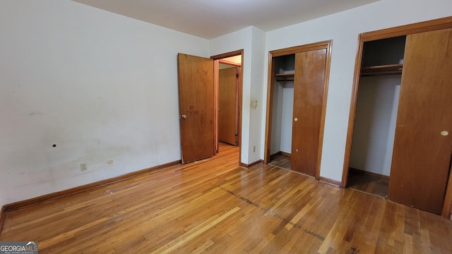 unfurnished bedroom featuring multiple closets and hardwood / wood-style flooring