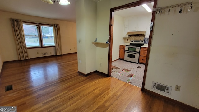 kitchen with backsplash, electric range, and light hardwood / wood-style flooring