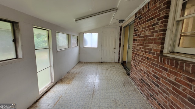 hallway with brick wall and vaulted ceiling