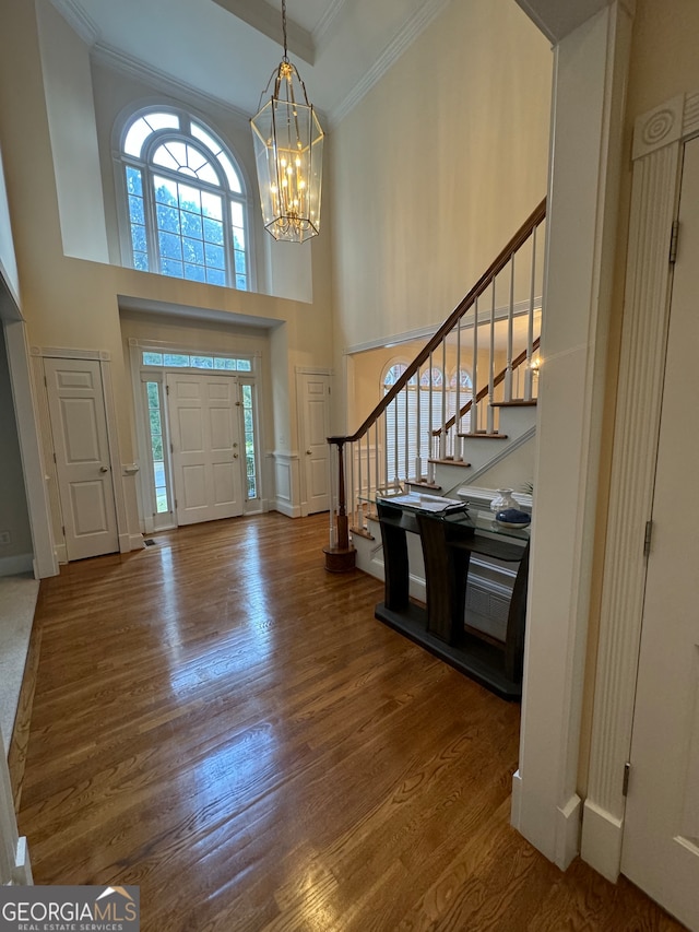 foyer featuring hardwood / wood-style floors, a chandelier, a high ceiling, and ornamental molding