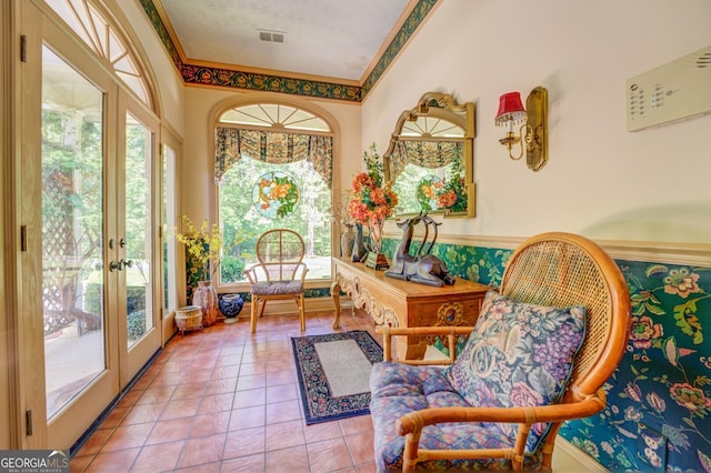 sitting room with a textured ceiling, crown molding, plenty of natural light, and french doors