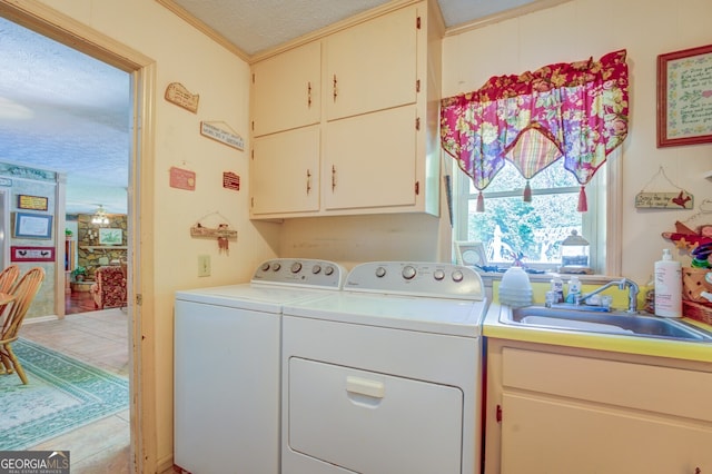 clothes washing area with cabinets, a textured ceiling, crown molding, sink, and washer and dryer