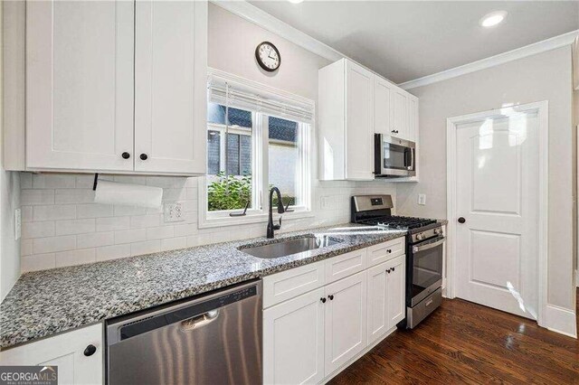 kitchen with white cabinetry, sink, light stone countertops, dark hardwood / wood-style flooring, and appliances with stainless steel finishes